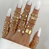 A hand displays a set of boho gold rings featuring vintage geometric, cross, heart, pearl, and butterfly designs.
