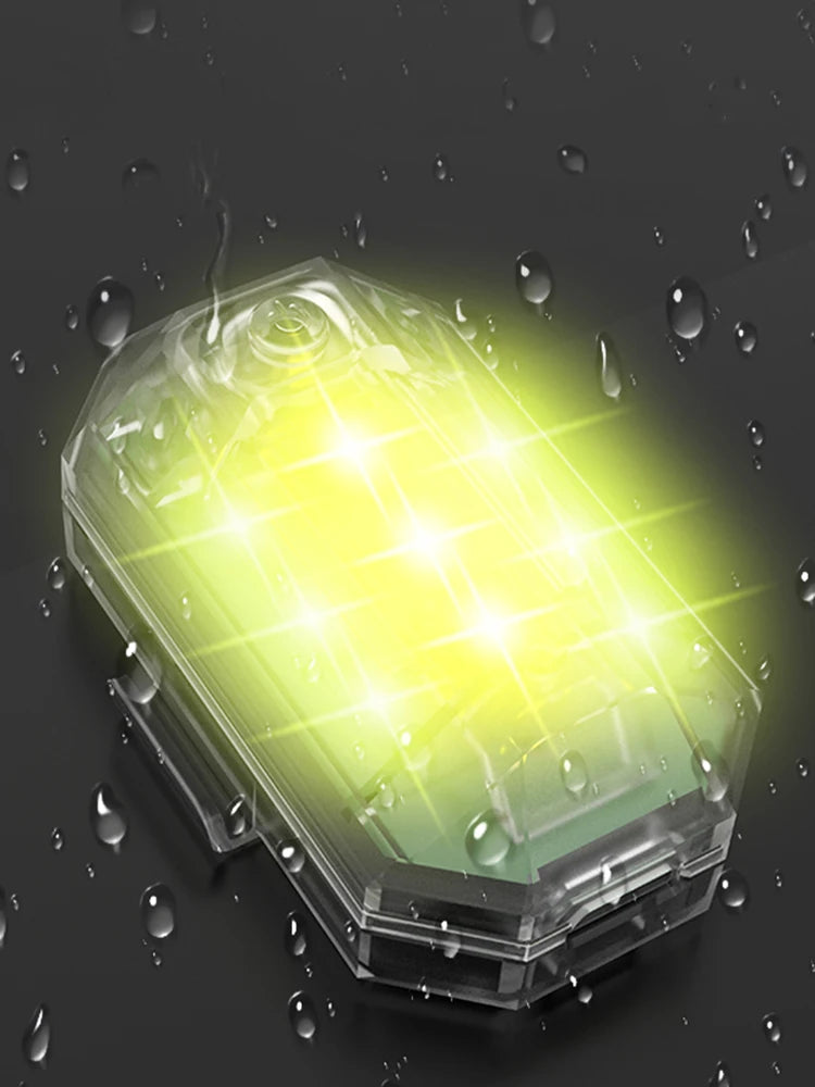 A transparent LED strobe light is illuminated with a bright yellow glow against a dark background, surrounded by water drople