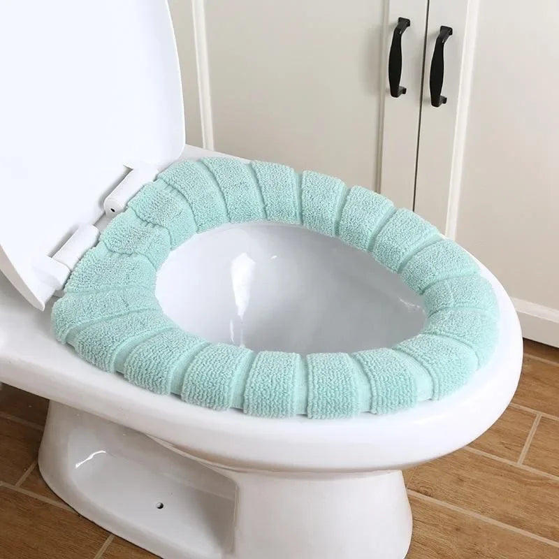 A white toilet features a light mint green textured seat cover designed to provide a soft surface.