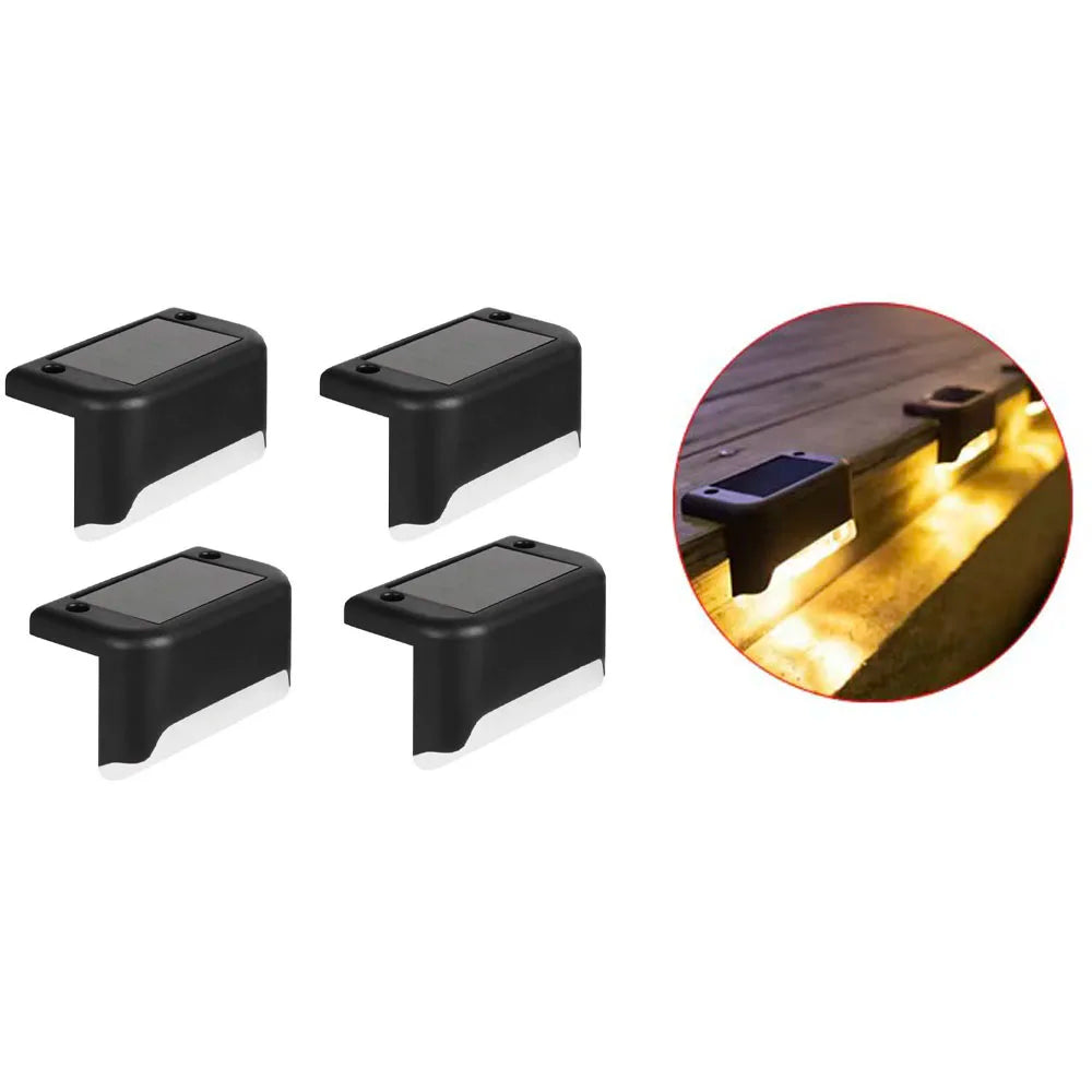 Four black solar powered deck lights illuminating an outdoor pathway or step.