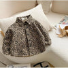 A leopard print denim shirt is displayed on a white sofa with a light-colored pillow.