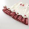 A white kids summer pinafore dress with a red and white plaid skirt featuring strawberry and bunny prints.
