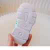 A close-up view of the sole of a white kids' breathable princess sandal being held by a hand.