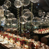 A ceiling decorated with numerous clear LED light-up balloons and string lights for an event.