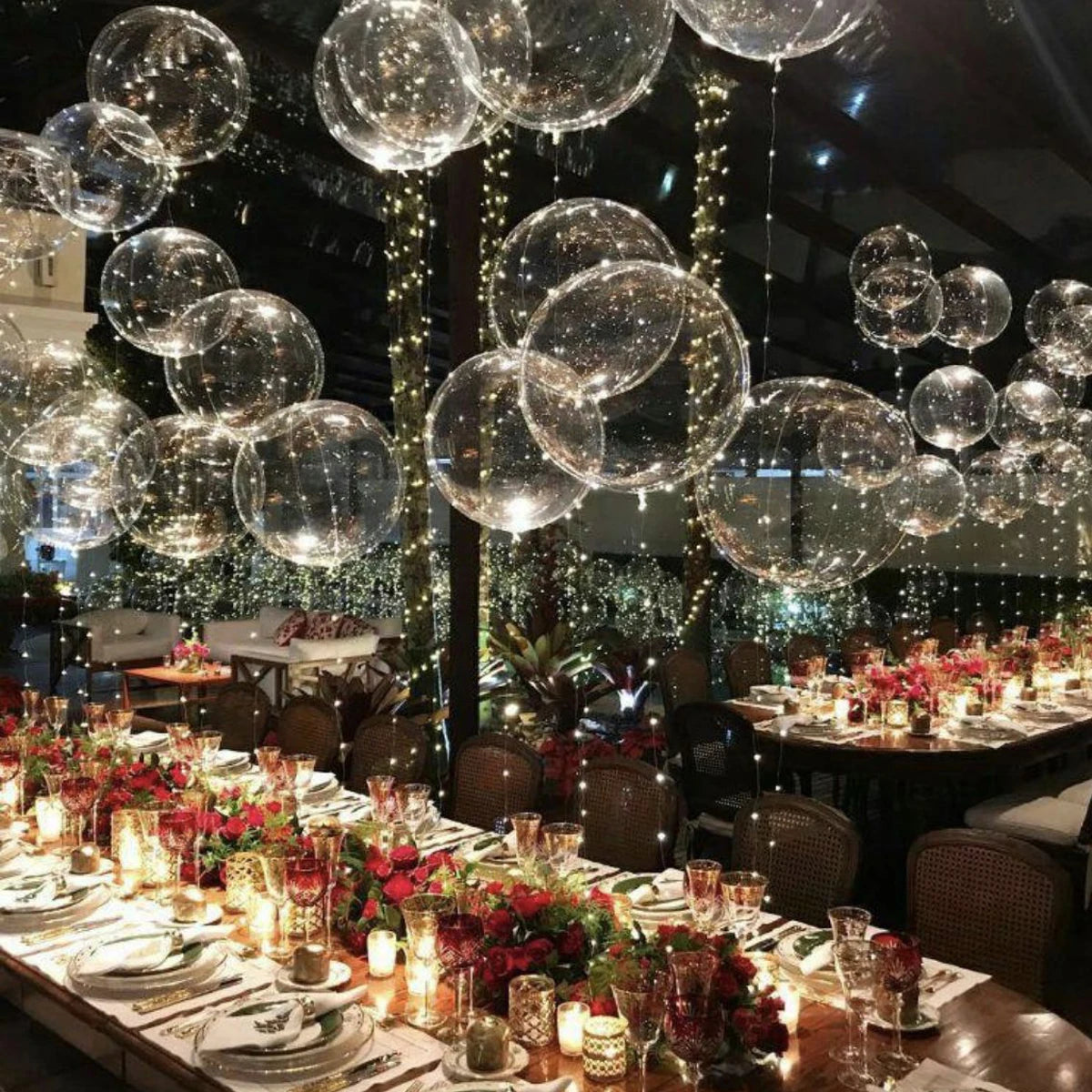A ceiling decorated with numerous clear LED light-up balloons and string lights for an event.