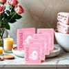 Rosa Collagen-Glow-Up-Maskentuben auf weißer Marmorplatte neben einer Rose und einer Kerze.