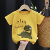 A yellow cartoon dinosaur t-shirt for toddlers hanging on a wooden hanger.