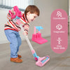 A young child is playing with a pink interactive toy vacuum cleaner, demonstrating coordination and imagination.