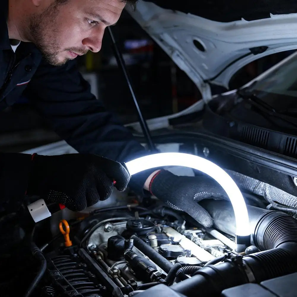 شخص يستخدم مصباح عمل LED من السيليكون المرن لإضاءة حجرة محرك السيارة.