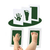 A set of white keepsake cards showing handprints and footprints in dark green ink on a black oval background.