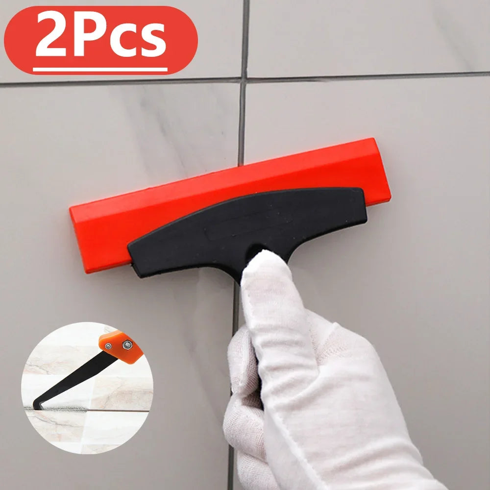 Two orange and black tile gap filling and cleaning scrapers being used to clean a tile surface.