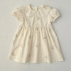 A light cream girls summer dress with floral embroidery and delicate Peter Pan collar details.