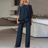 En kvinne modellerer et marineblått todelt sett med off-shoulder topp med gjennomsiktige ermer og vide buksebein.