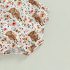 A white baby romper featuring a brown cow print with floral accents and a matching headband.