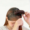 A woman is using an invisible hair root lifter comb to style her hair.