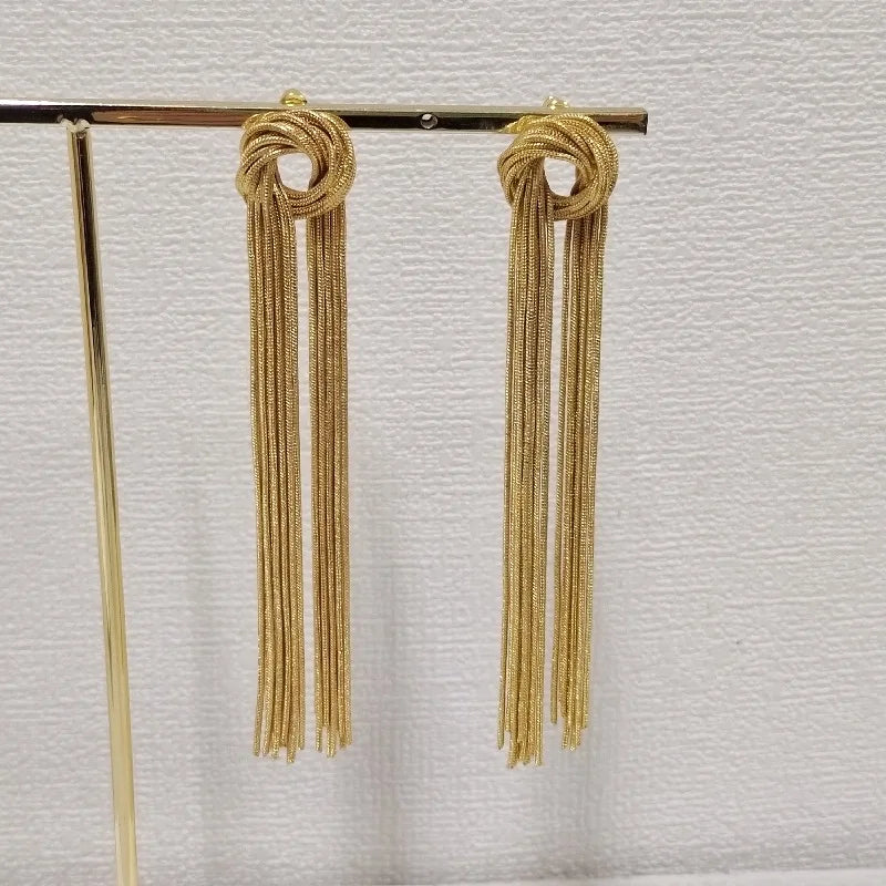 Gold geometric tassel drop earrings hanging on a wooden rod