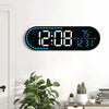 A large digital wall clock displaying time, temperature, and day of the week on a white wall.