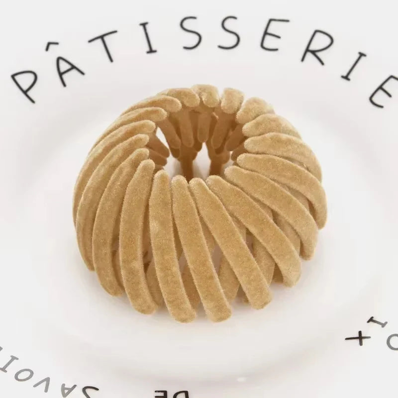 Nærbilde av et gyllent fugleredehårspenne til hestehaler på en hvit tallerken.