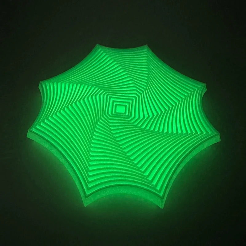 Et glødende grønt geometrisk fidget-leketøy med et spiralformet optisk illusjonsdesign.