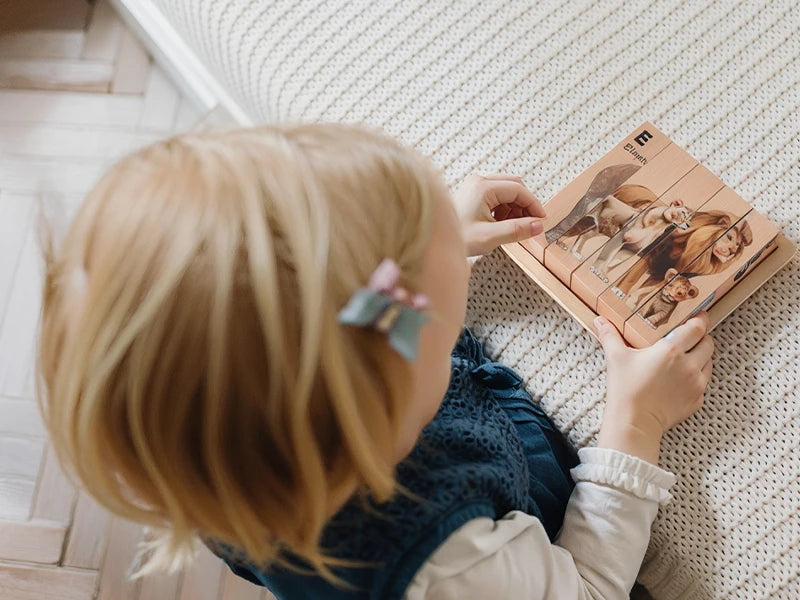 A young child is looking at a wooden safari animal puzzle set with several animal figures.