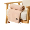 A beige knitted shawl draped over a wooden chair, showing the texture and fold of the fabric.