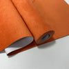 Rollo de tela de gamuza naranja con acabado aterciopelado en primer plano.