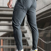 A man wearing dark gray high-stretch joggers with white sneakers standing on a staircase.