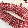 A red and white plaid pinafore dress with a ruffled skirt is shown next to a white top featuring strawberry and bunny prints.