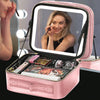 A pink LED lighted makeup case with a mirror is open, showing various cosmetic tools inside.
