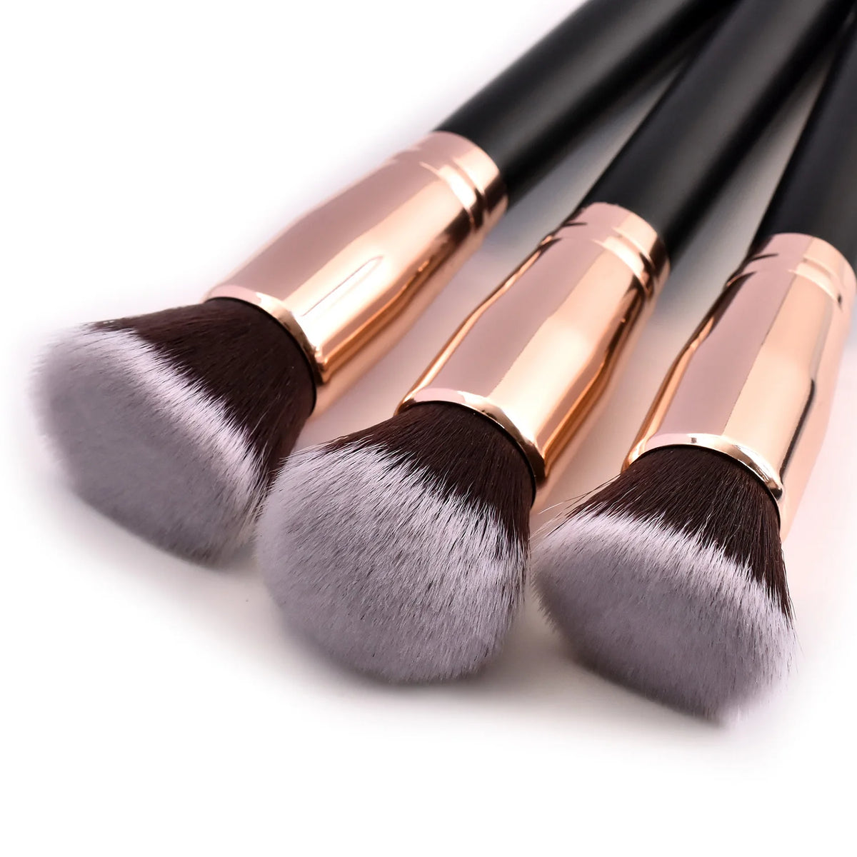 A set of professional makeup brushes with pink metal ferrules and dark gray bristles.