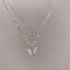 A silver double-layer necklace featuring a butterfly pendant and a small charm.