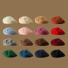 A collection of ten wool beret hats in various shades including cream, beige, orange, pink, red, and dark blue.