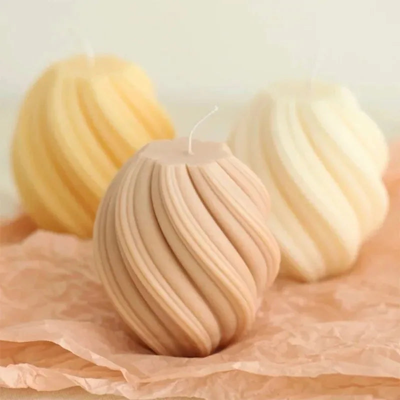 A close-up of a beige pillar candle with a wavy texture, set on crumpled brown paper.