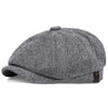 A grey and black patterned vintage newsboy cap or octagonal beret shown from the side.