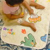 A baby is lying on a waterproof mattress protector featuring a dinosaur design.