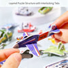 A hand holds a purple and white foam airplane puzzle piece from a layered puzzle structure.