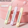 A set of two multifunctional needle threaders in light green and purple plastic are displayed on a pink background.