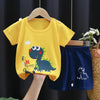 A yellow dinosaur print kids t-shirt and shorts set hanging on a wooden hanger.