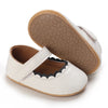 A pair of soft white baby first walker shoes with tan soles and stitched details.