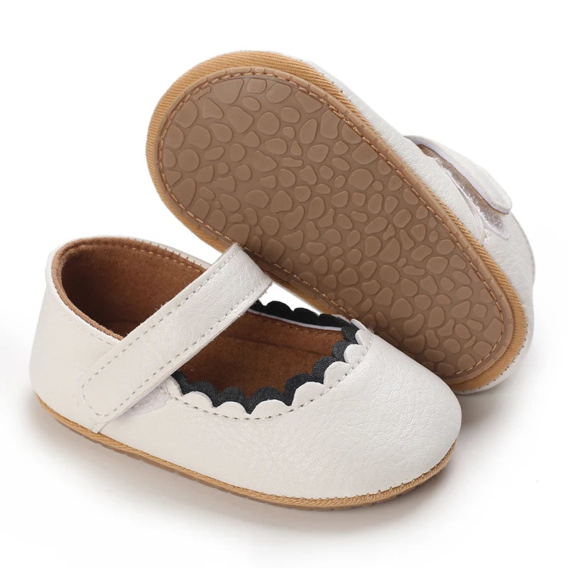 A pair of soft white baby first walker shoes with tan soles and stitched details.