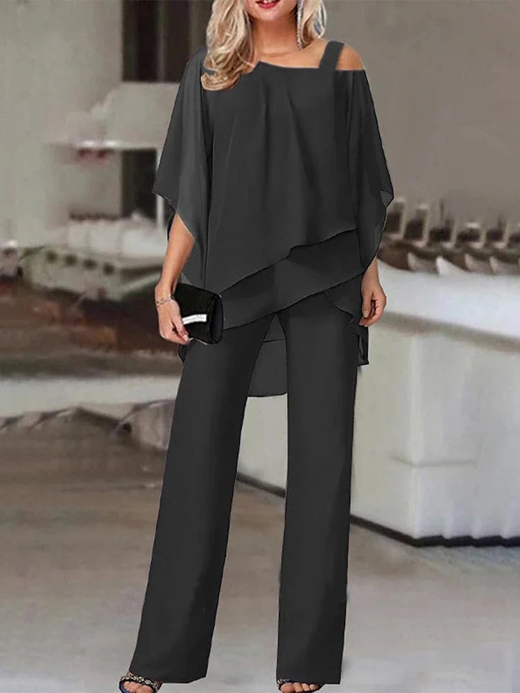 En kvinne modellerer et koksgrått todelt sett med off-shoulder topp og vide bukser.