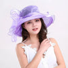 A woman models a purple organza sun hat with ruffled mesh and a white top.