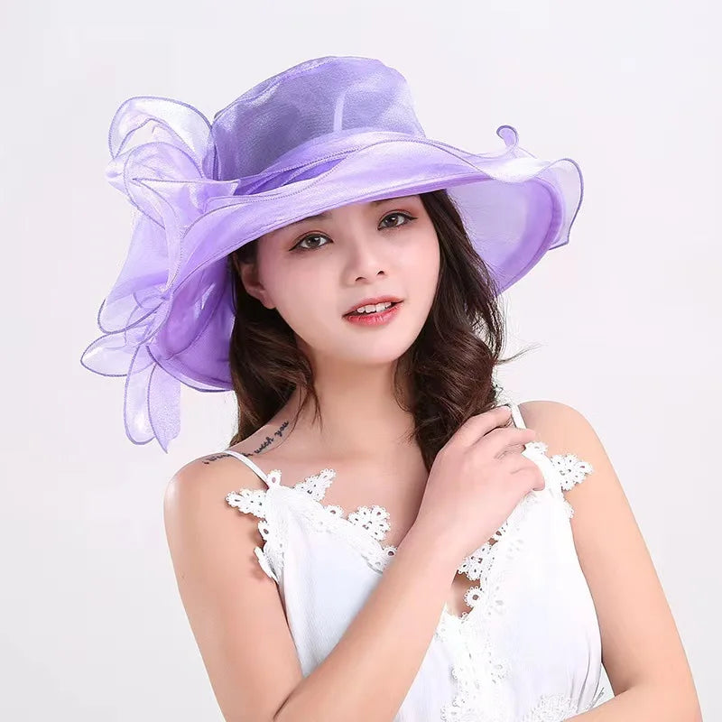 A woman models a purple organza sun hat with ruffled mesh and a white top.