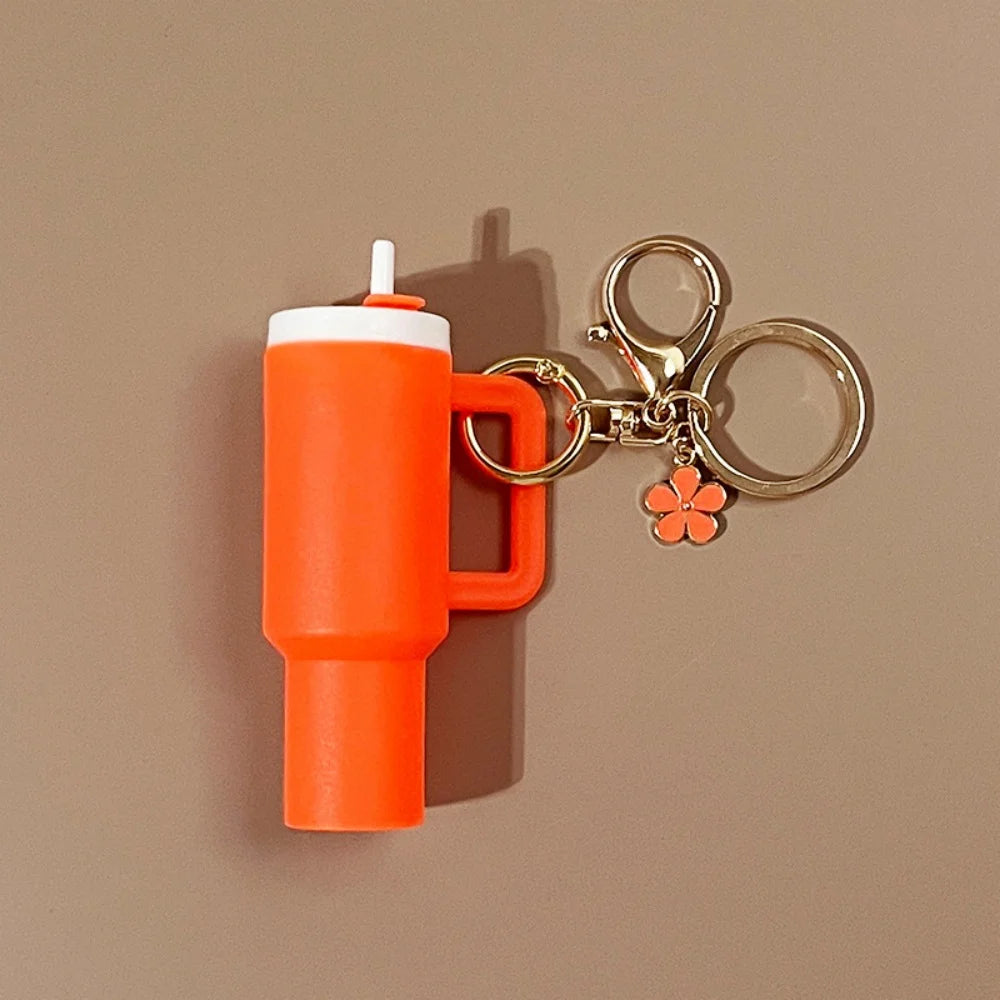 Orange mini tumbler på nøglering med karabinhage og blomstervedhæng.