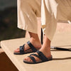 A pair of women's cork footbed slide sandals in dark gray suede resting on a light-colored surface.