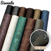 Rolls of vintage floral textured faux leather fabric in various shades of brown, green, and blue.