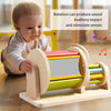 A wooden spinning drum toy for toddlers is shown next to a baby, demonstrating sound and sensory stimulation.