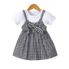 Girls' cotton knit dress with a black and white plaid pattern and a bow, displayed on a hanger.