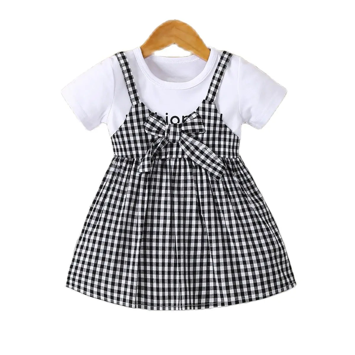 Girls' cotton knit dress with a black and white plaid pattern and a bow, displayed on a hanger.
