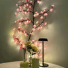 Dekorativ lampa med rosa körsbärsblommor och dimbara LED-lampor på vit yta.